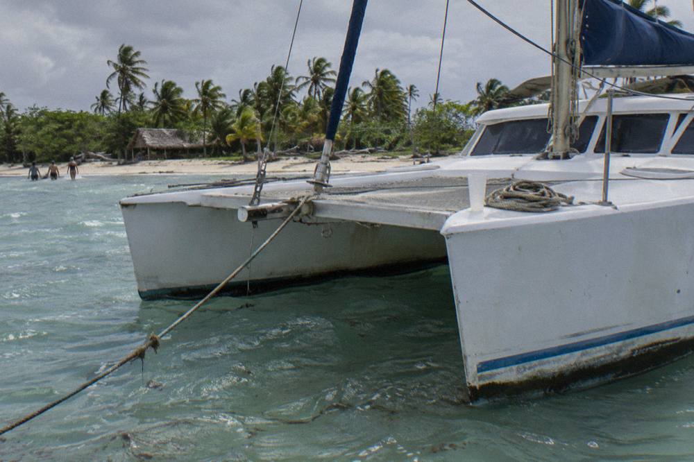 Catamaran moored in clear shallow water near a sandy Caribbean beach