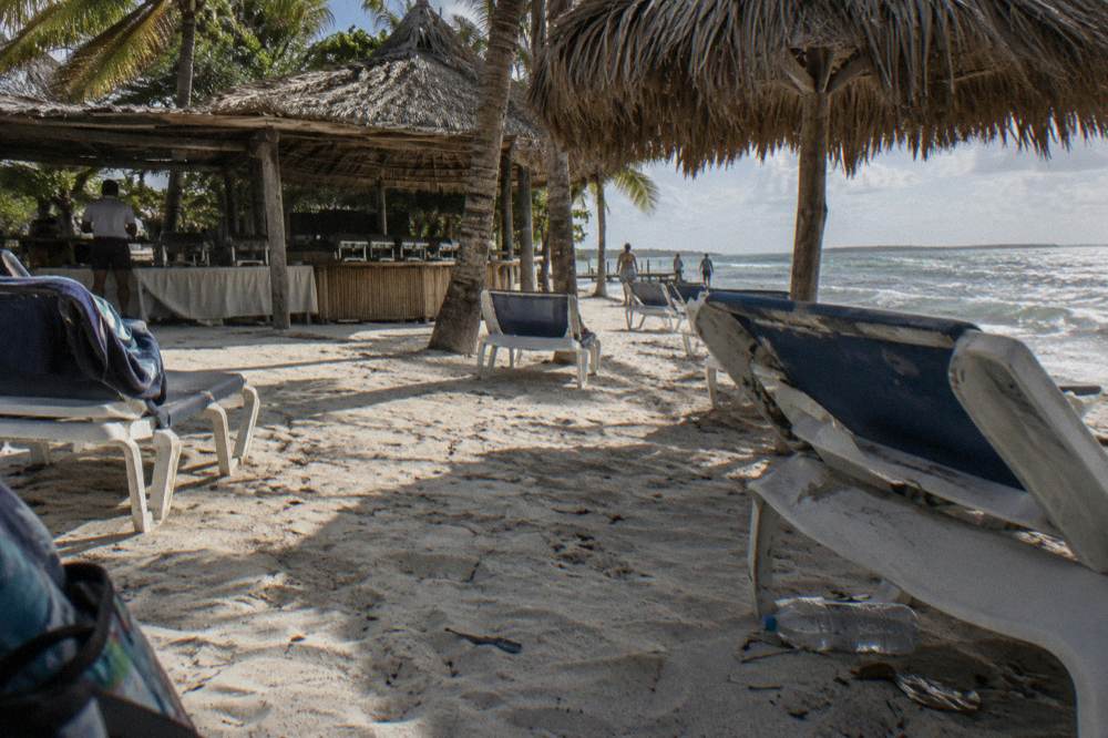 Shaded beach lounge chairs and thatched umbrellas on white sand at midday
