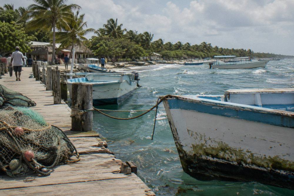 Wooden tour boats moored along a small Caribbean fishing village pier in morning light