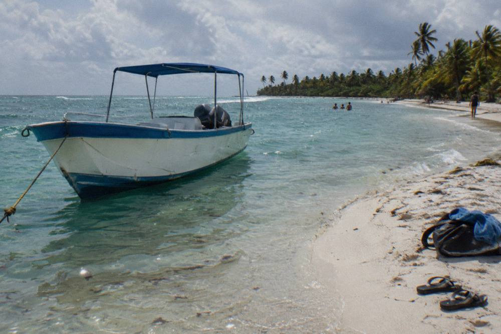 Speedboat anchored in shallow turquoise water near a sandbar at Saona Island