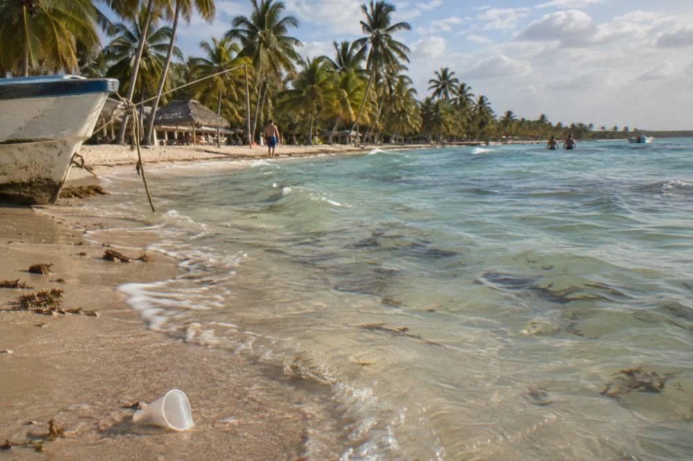 Wide empty white sand beach with shallow turquoise water and a line of palm trees