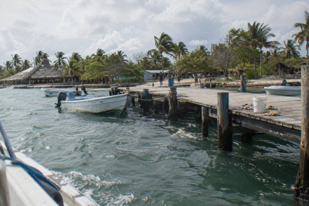 Small boats moored at a wooden pier above clear green water