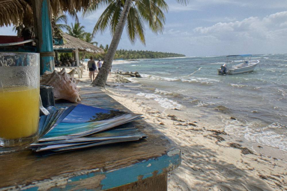 Wooden tour desk with brochures under palm trees beside a resort walkway