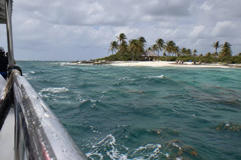 Open Caribbean water with whitecaps and scattered clouds beyond a boat railing