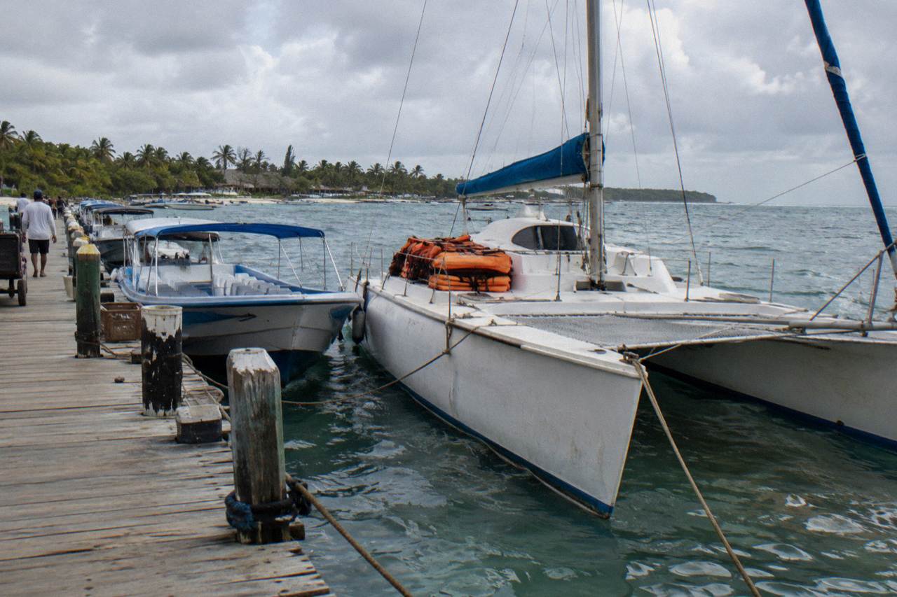 Moored catamarans and speedboats at a Caribbean marina pier on a calm morning