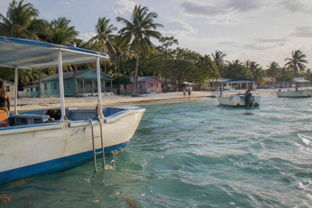 Tour boats anchored in calm turquoise water beside a wide Caribbean beach