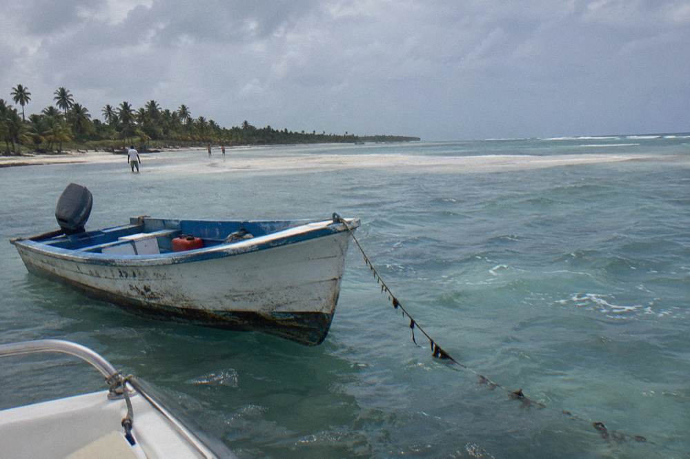 Speedboat anchored in shallow blue water beside a sandbar near Saona Island