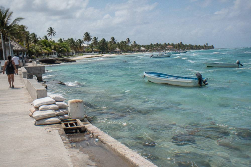 Shallow turquoise water at a palm-lined Caribbean village beach with small fishing boats at anchor
