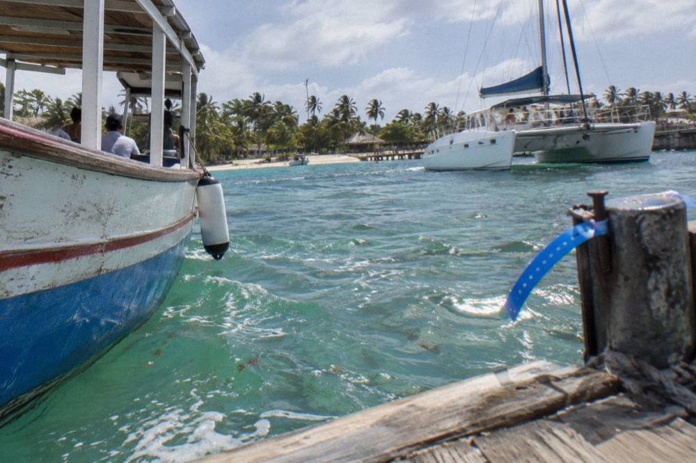 Wooden excursion boats and catamarans moored at a small Caribbean departure pier in morning light