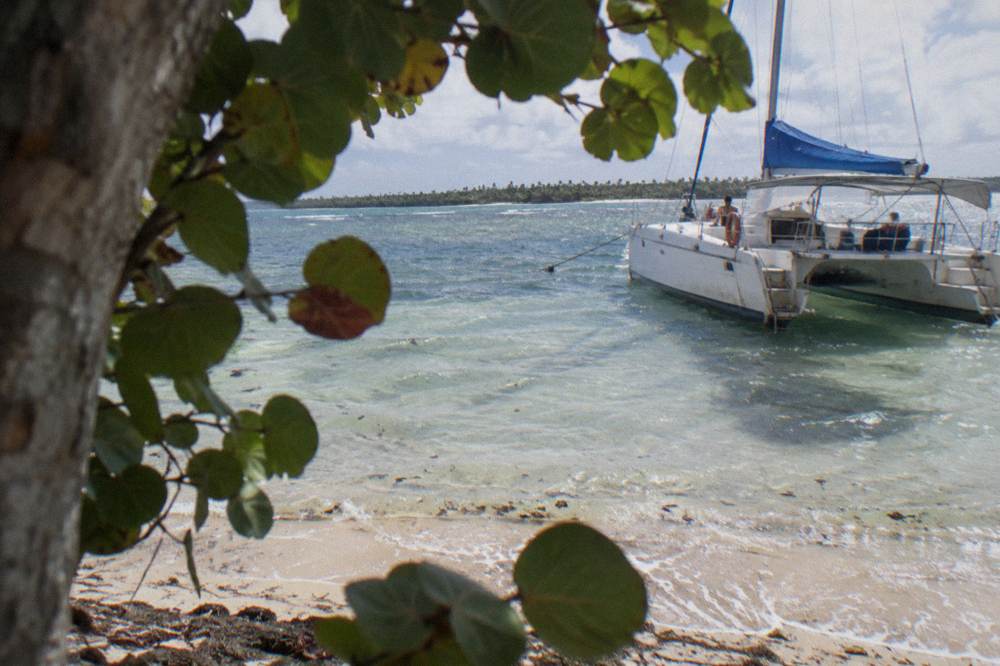 A catamaran anchored off a pale sand Caribbean beach with clear shallow water