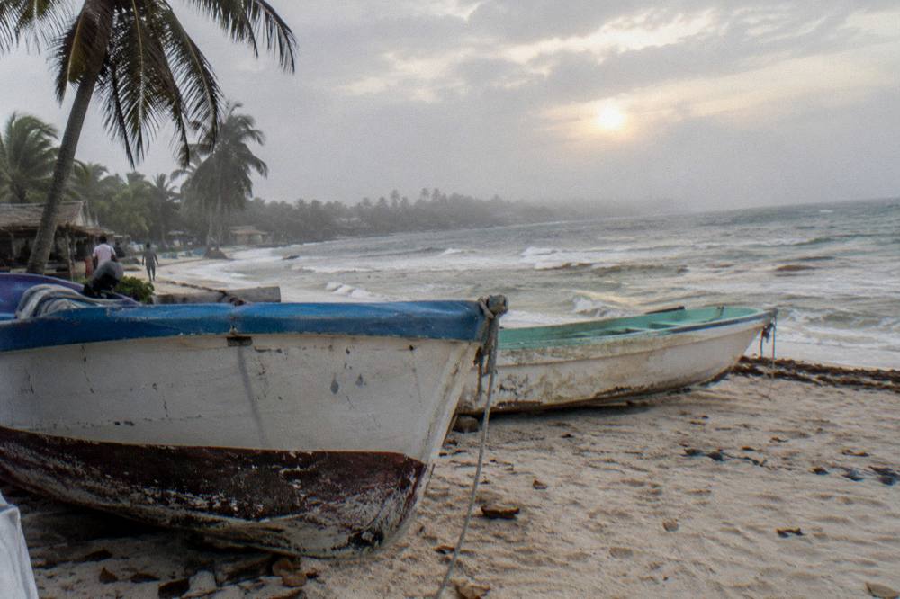 Small fishing boats resting on pale sand beside clear shallow water in early morning light