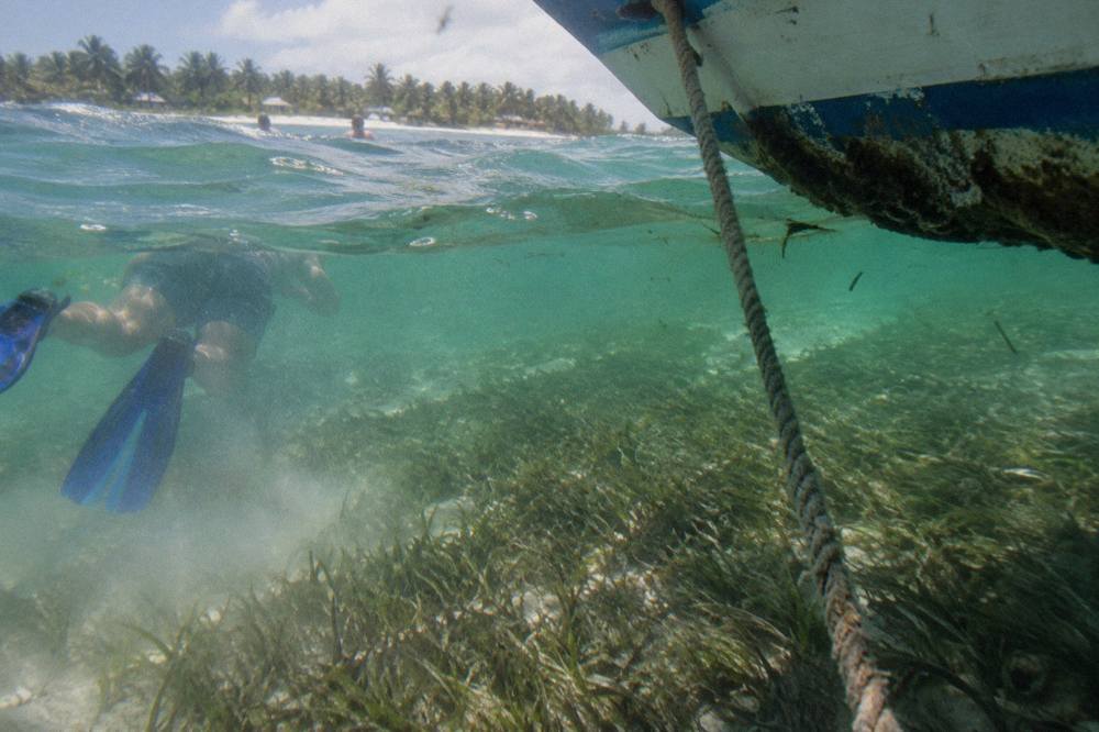 Clear shallow water over a sandy bottom with patches of seagrass near a moored boat