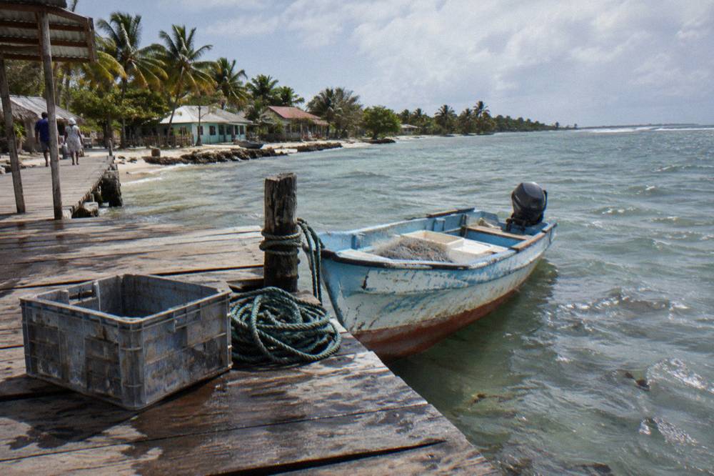 Small wooden fishing boat moored at a village dock beside calm shallow water