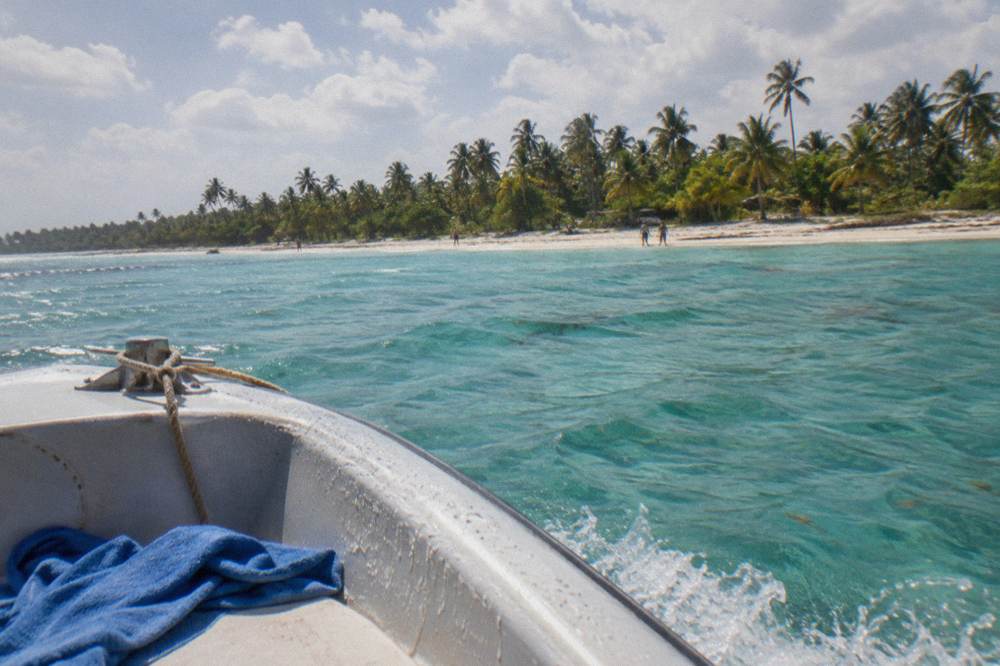 Speedboat crossing clear turquoise water toward a palm lined island