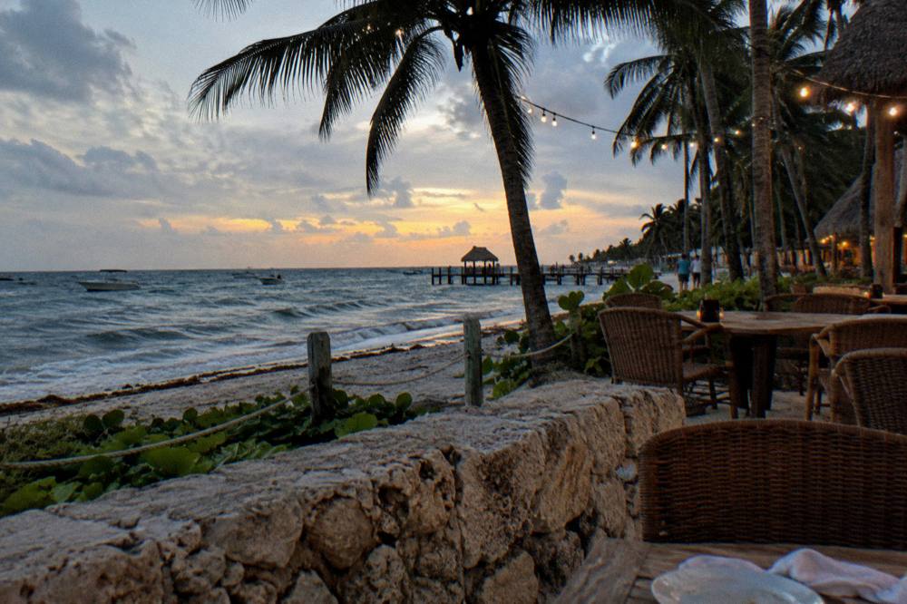 An evening beach scene with a small restaurant terrace under palm trees