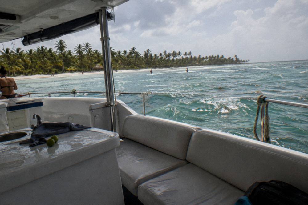 A shaded catamaran deck with cushioned bench seating and a small bar counter