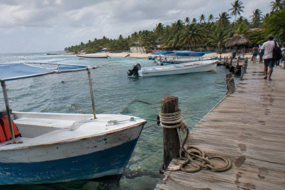 Small boats moored at a wooden pier over clear shallow water in the morning