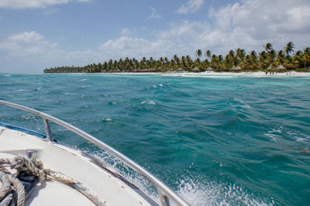 Speedboat cutting across open turquoise water toward a distant island