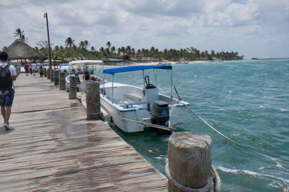 Wooden pier stretching into calm turquoise water with tour boats moored alongside