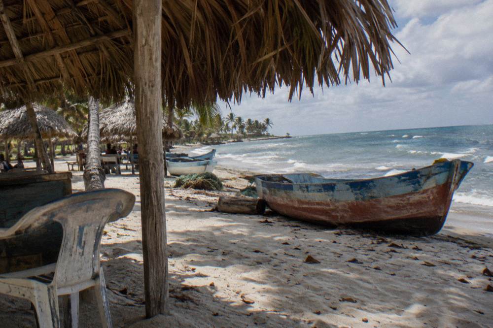 Shaded palm thatch palapas on white sand above calm clear water
