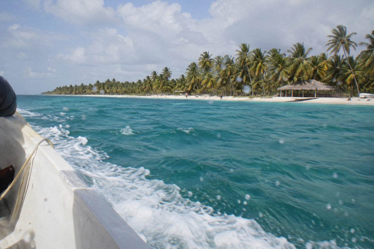Speedboat crossing turquoise Caribbean water toward the palm-lined shoreline of Saona Island