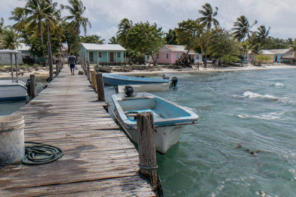 Tour boats moored along a wooden pier at a Caribbean fishing village in early morning light