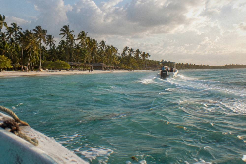 Speedboat cutting across calm turquoise water toward an island beach