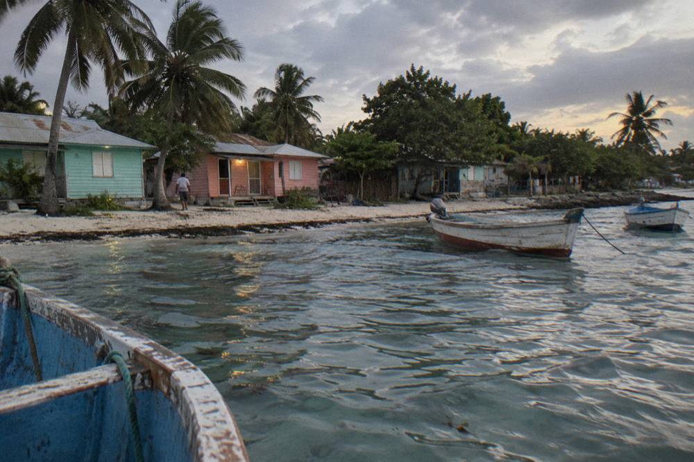 Wooden fishing boats moored beside pastel houses along a small island village shoreline