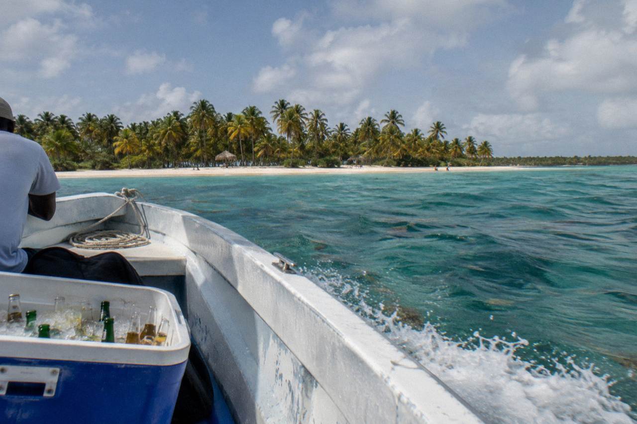 A private speedboat cruising over turquoise Caribbean water toward palm-fringed Saona Island