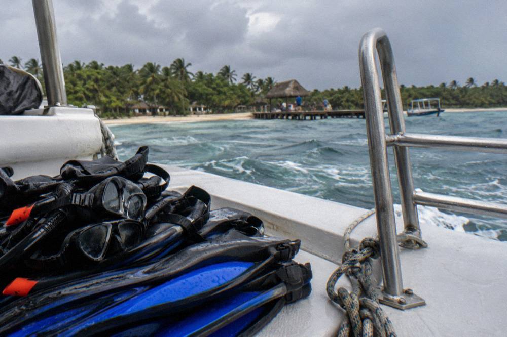 Snorkel masks and fins stacked on a boat deck beside a ladder