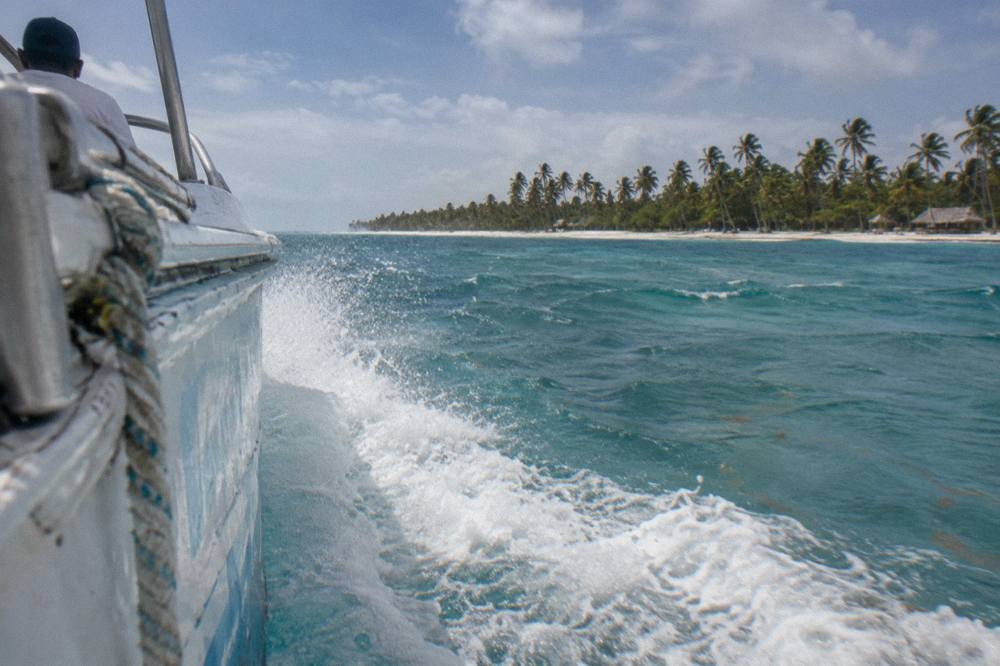Speedboat riding across open turquoise Caribbean water with spray coming off the bow