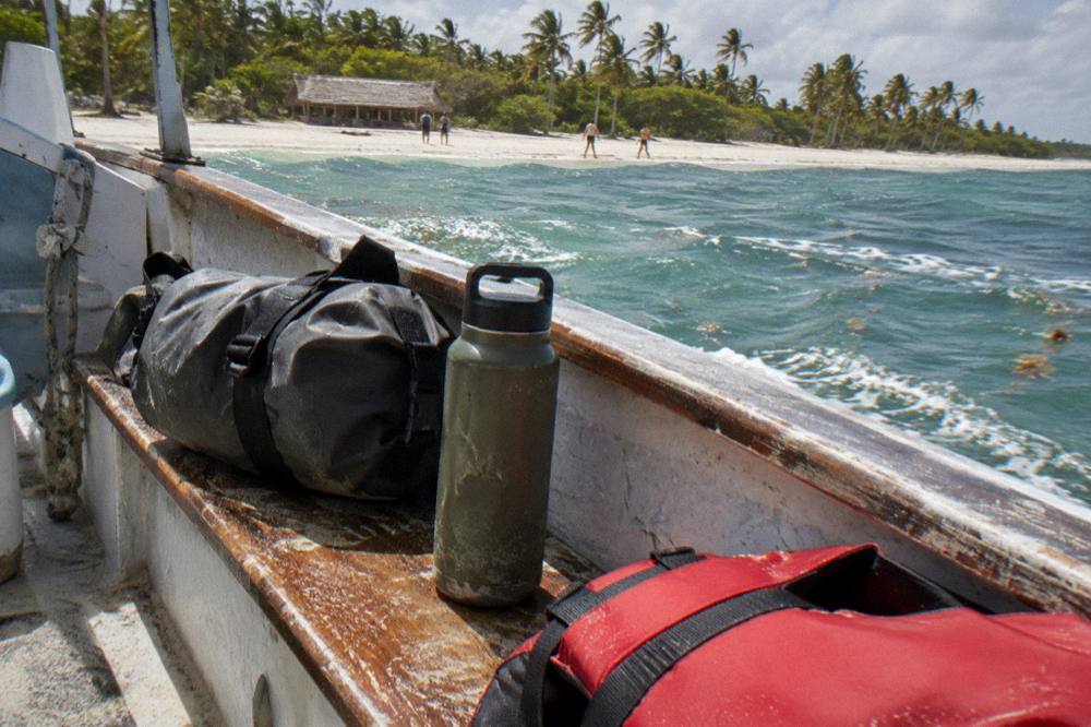 Dry bag and reusable water bottle packed on a boat bench beside a life jacket