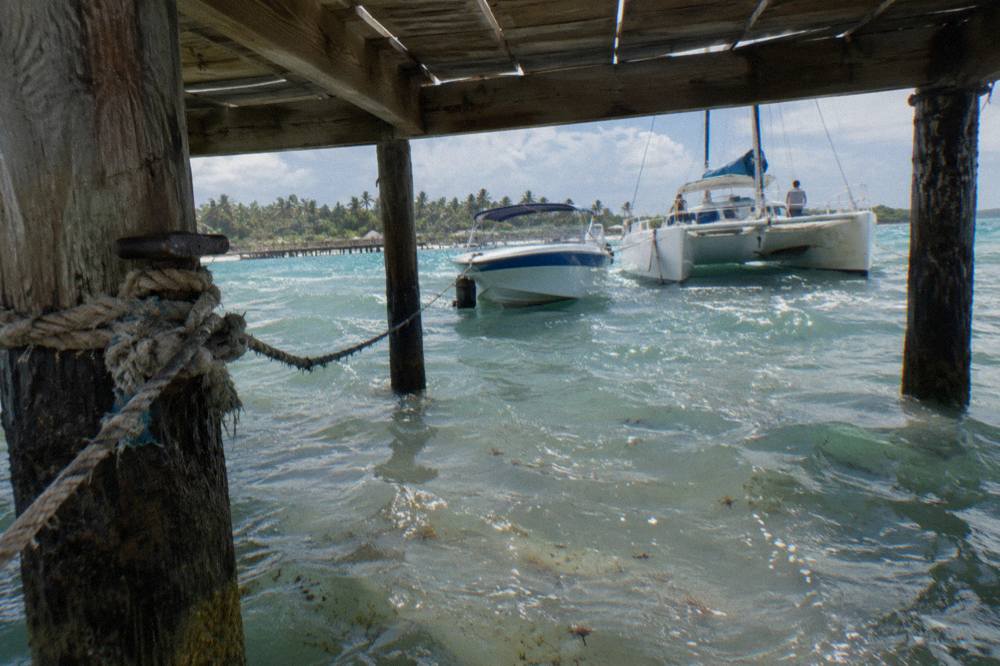 Speedboat and catamaran tied side by side at a small Caribbean dock