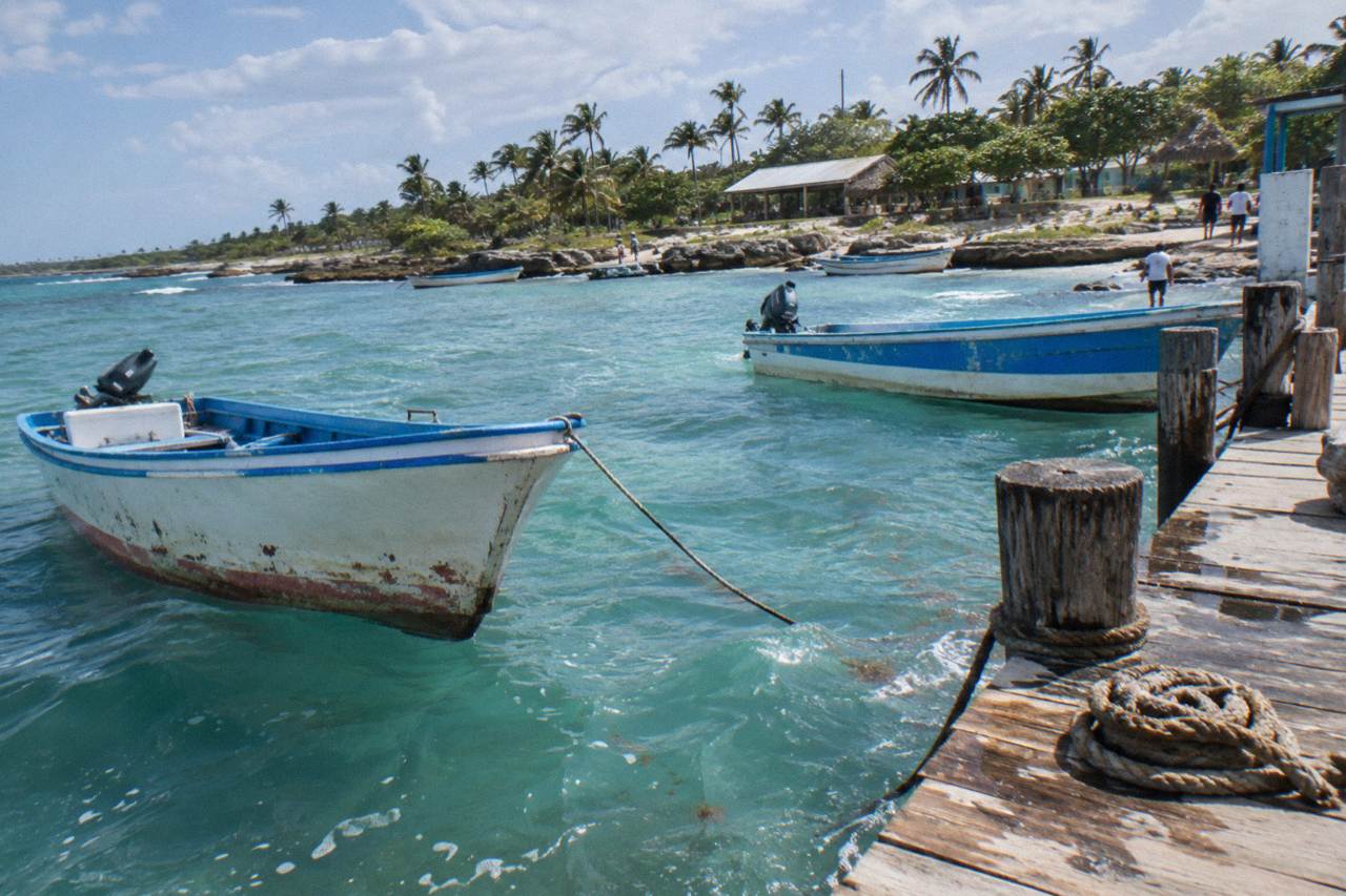 Wooden boats moored in clear turquoise water at a Caribbean fishing village pier
