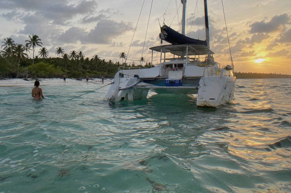 Catamaran moored in shallow turquoise water near a sandbar