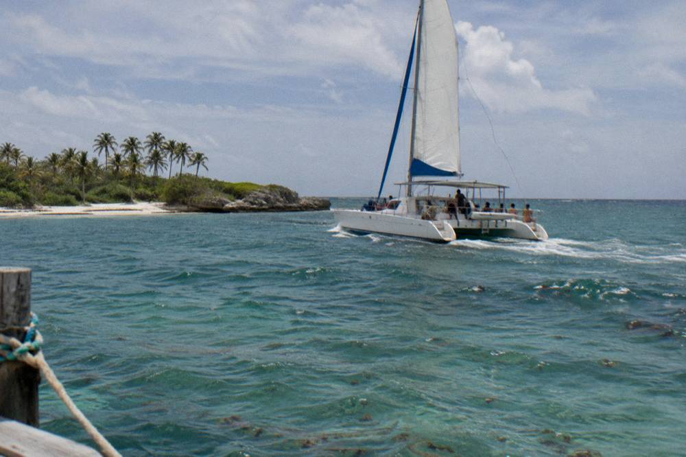Open catamaran with passengers sailing on calm Caribbean water