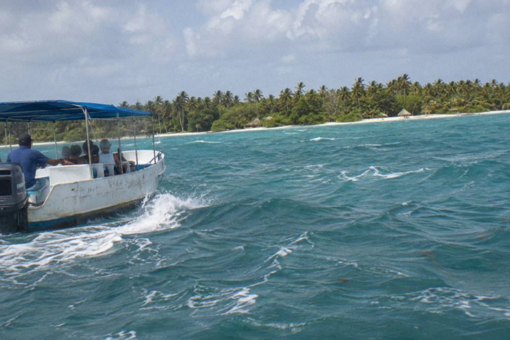 Speedboat cruising across open turquoise Caribbean water toward an island