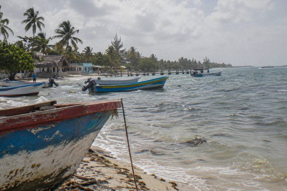Colorful fishing boats resting on a small Caribbean village beach beside calm water