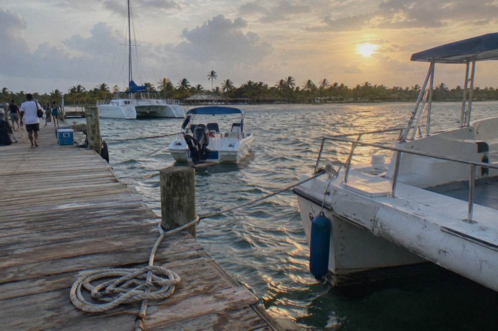 A wood pier with moored catamarans and speedboats in a small Caribbean harbor
