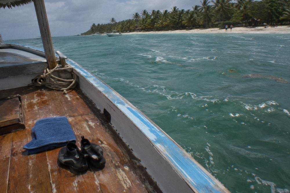 Water shoes and a folded dry towel on the wooden deck of a small boat
